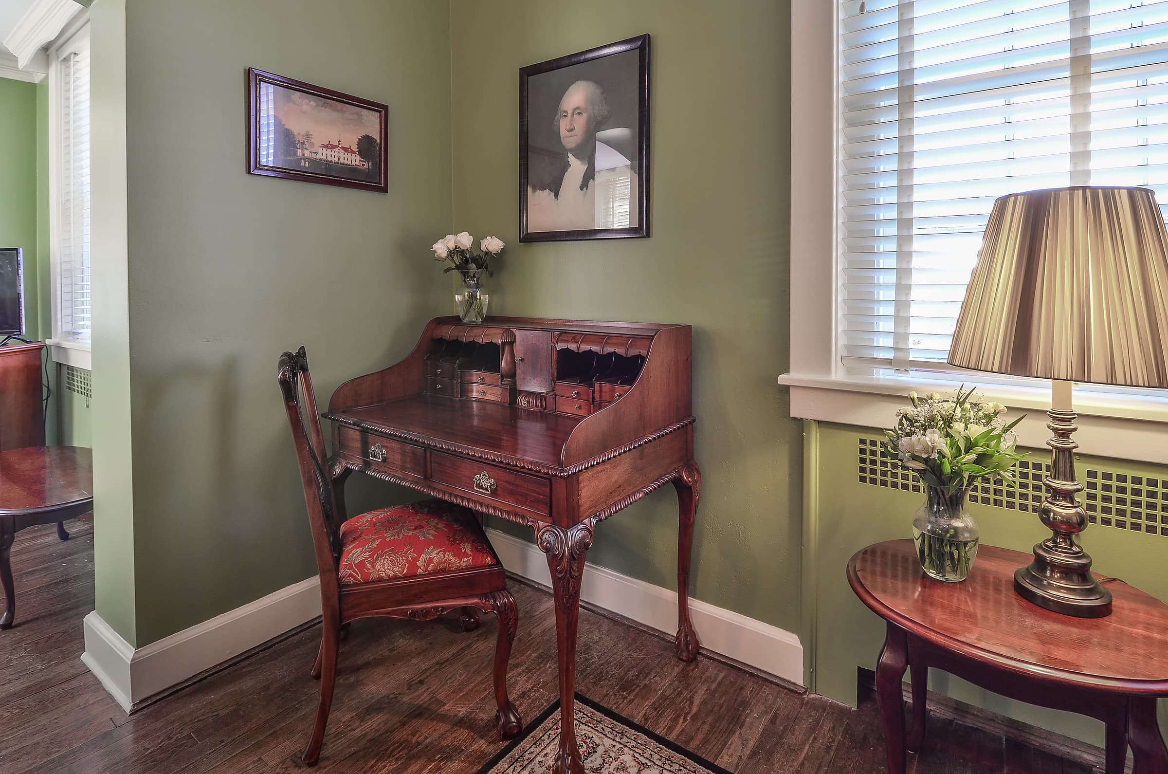 Antique desk and chair with red velvet cushion, wooden side table with lamp