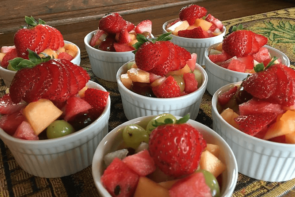 A refreshing fruit salad: The cups are arranged neatly on a wooden table, making it a visually appealing and appetizing dish.