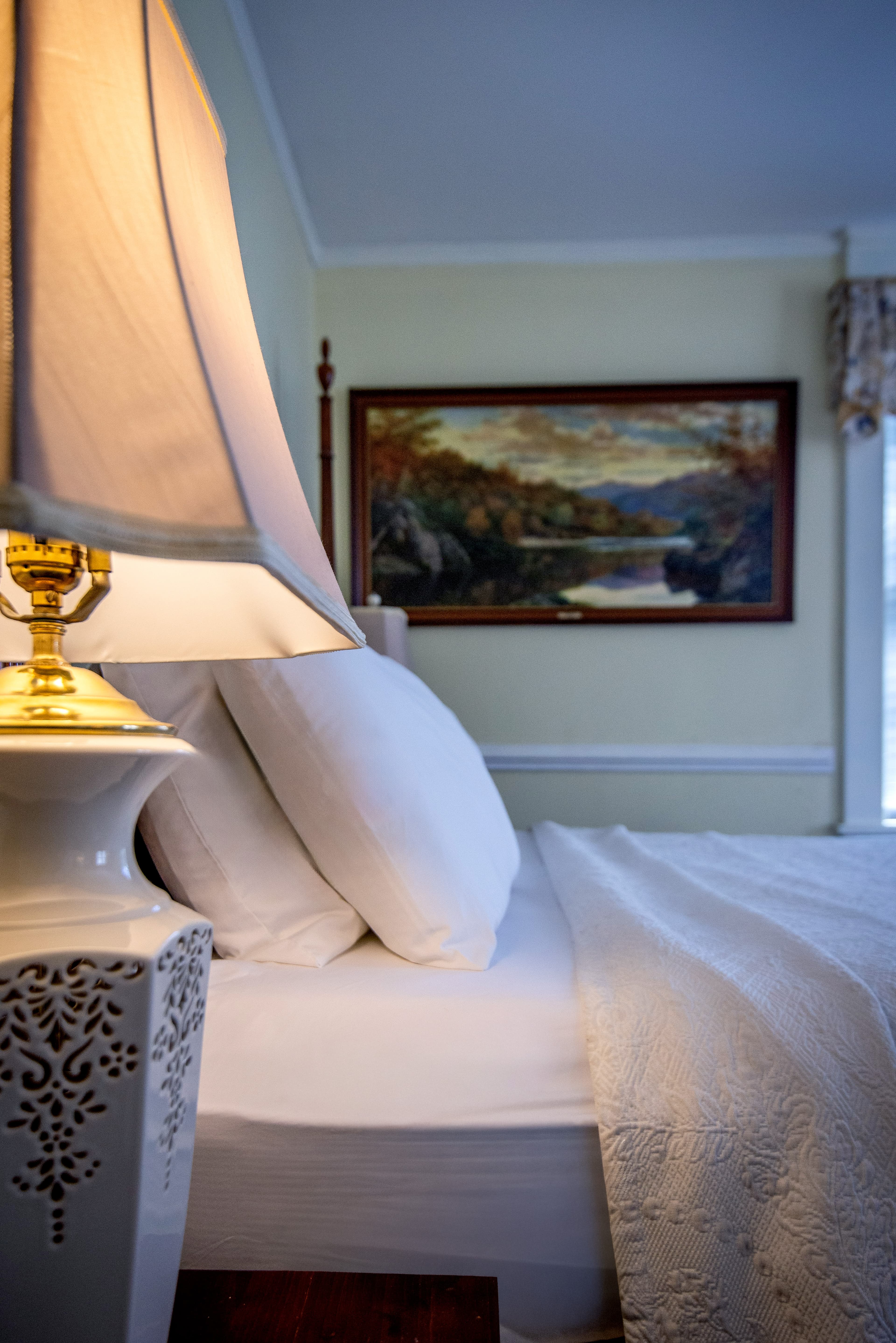 A cozy bedroom scene featuring a lamp and neatly arranged pillows.