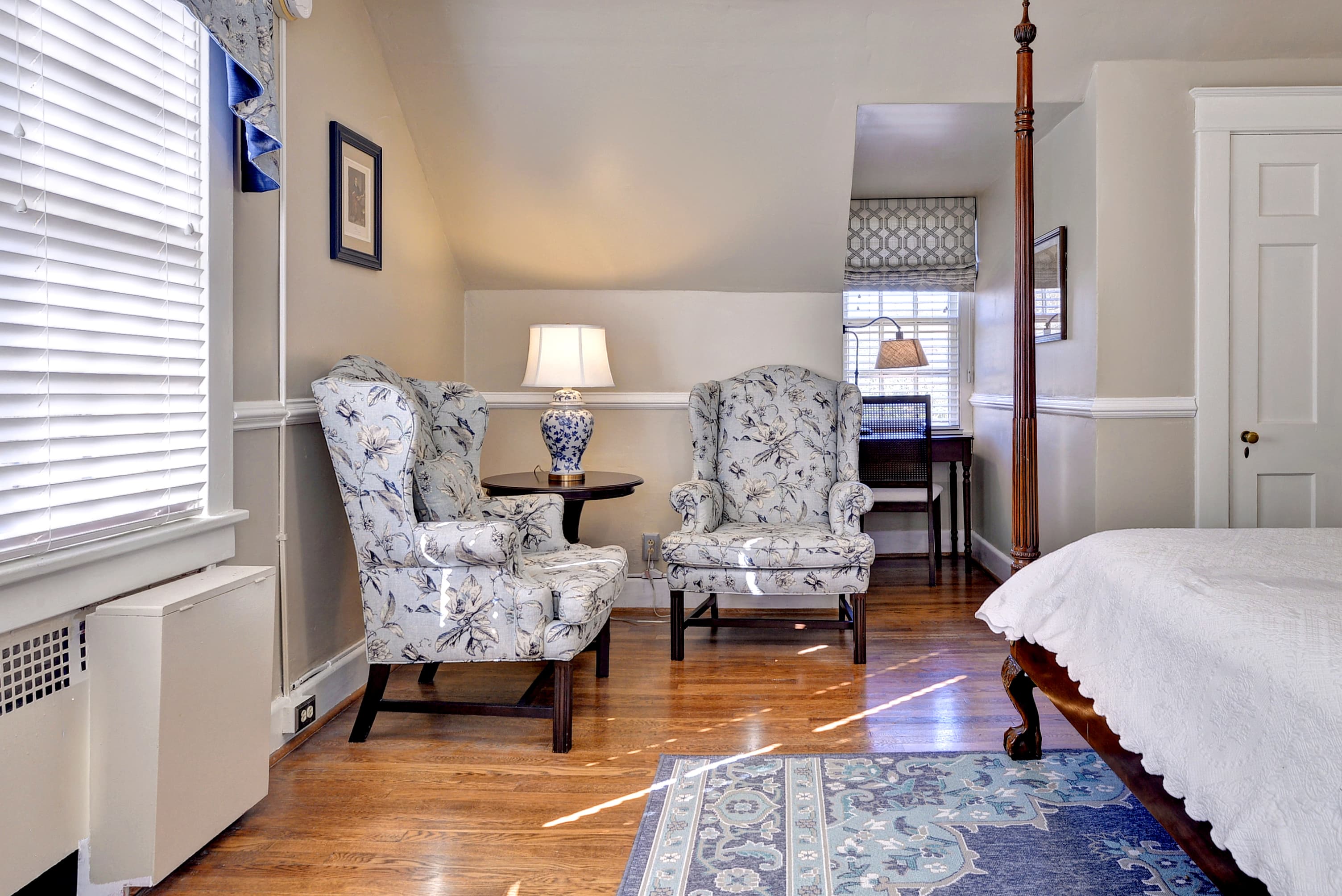 Cozy room featuring floral-patterned armchairs, a table with a lamp, and a decorative rug.