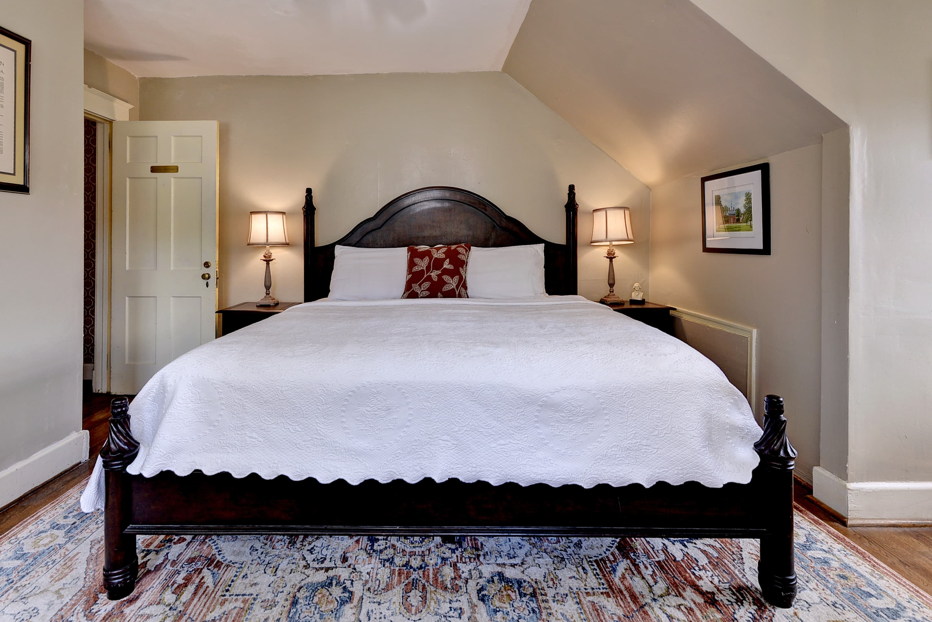 A cozy bedroom featuring a large bed with a white bedspread, two bedside lamps, and tasteful decor.