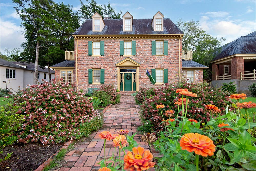 Photo of front walkway of red brick 2 story bed and breakfast with dormers in attic