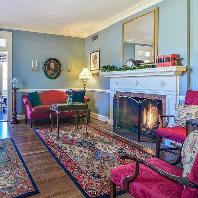 interior photo of guest area with carpeted red sitting areas and a mirror hung over a large mantel fireplace adorned with a clock