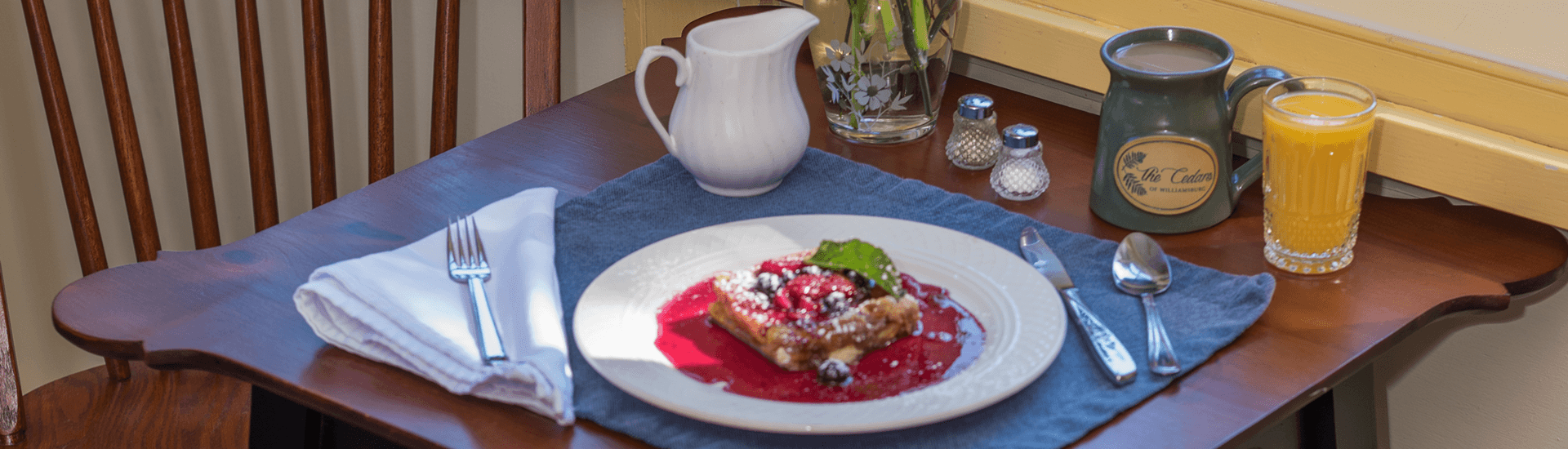 A cozy breakfast nook: The setting features a wooden table, chairs, and a large window overlooking greenery.