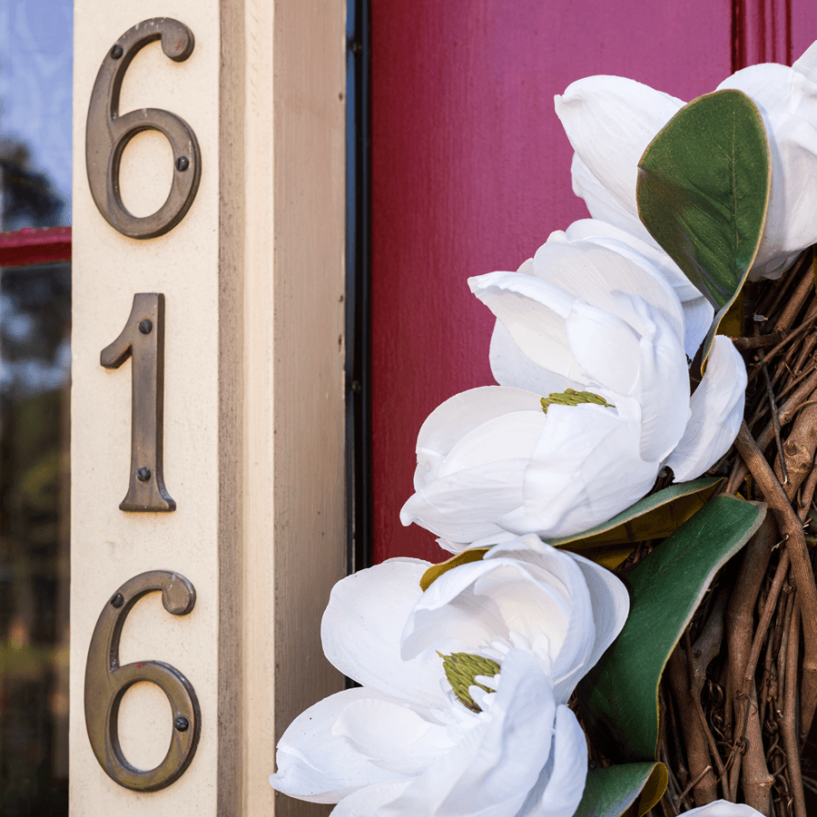 A close-up of a house number: The numbers '616' are displayed on a white post next to a red door.