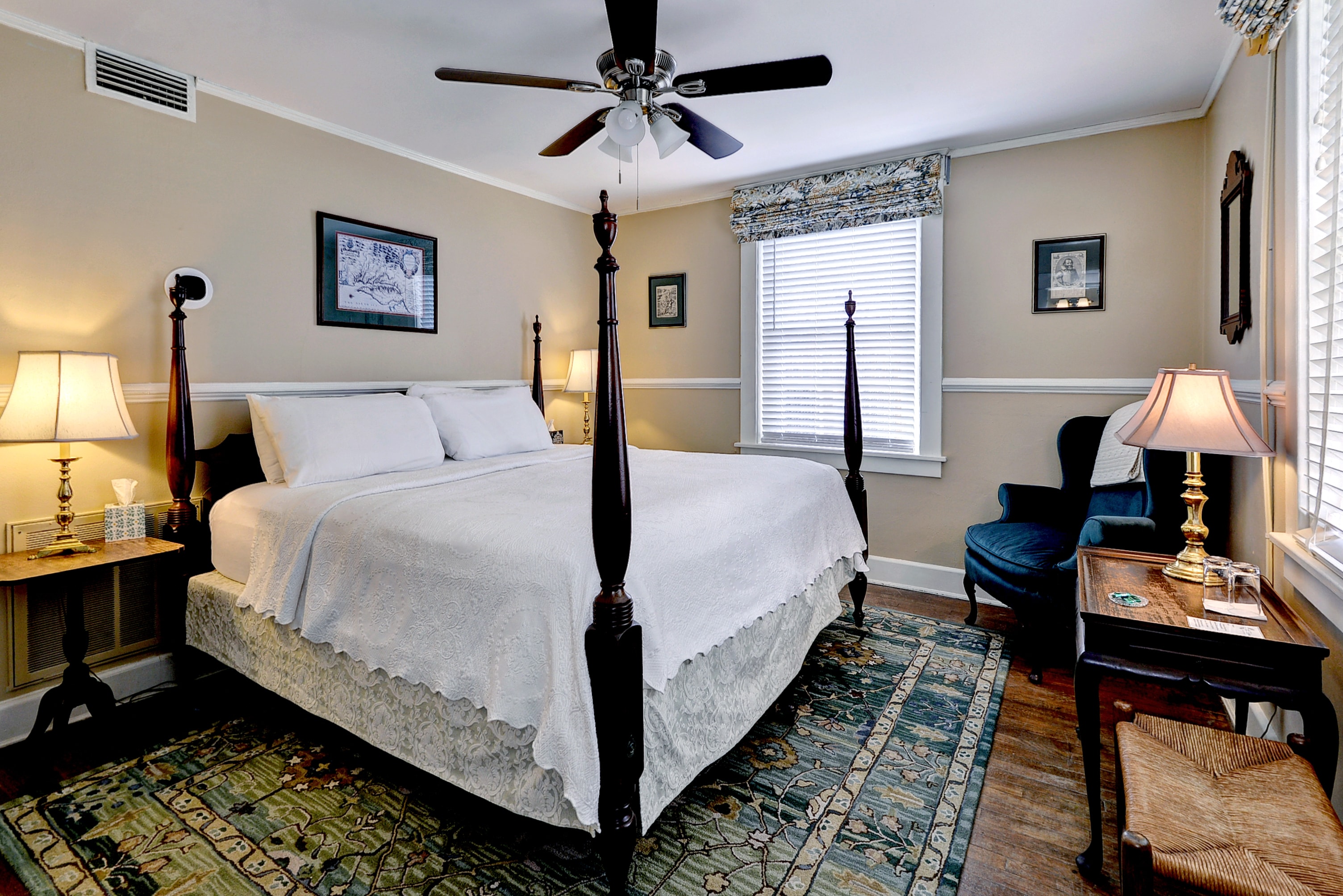 Cozy bedroom with a four-poster bed, two lamps, and a comfortable chair.